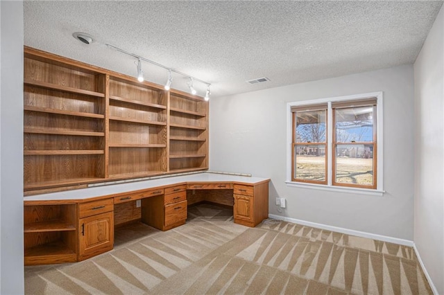 unfurnished office featuring light carpet, built in study area, visible vents, and baseboards