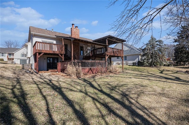 rear view of house featuring a chimney, a deck, and a lawn