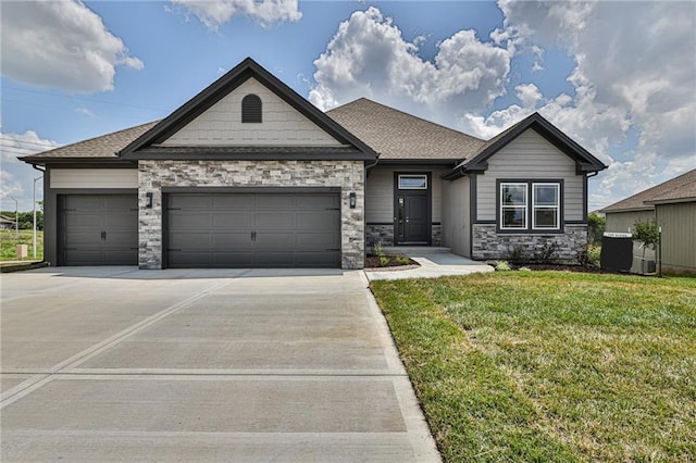 view of front of property with concrete driveway, stone siding, roof with shingles, an attached garage, and a front lawn