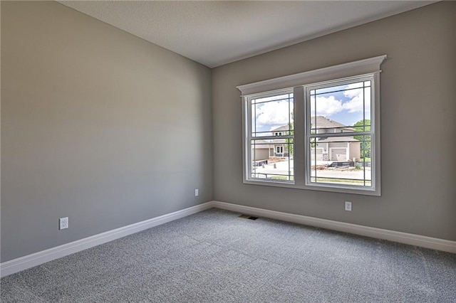 spare room featuring a textured ceiling, carpet flooring, visible vents, and baseboards