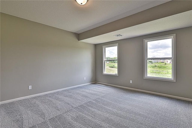 carpeted empty room with baseboards, visible vents, and a textured ceiling