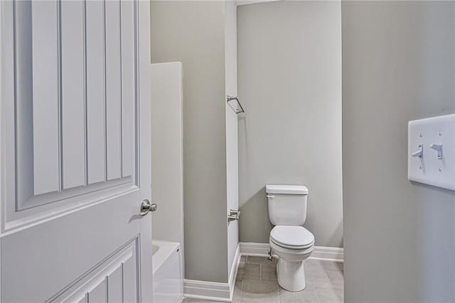 full bath with a tub to relax in, tile patterned floors, toilet, and baseboards