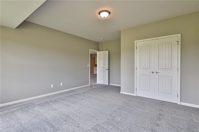 unfurnished bedroom featuring a closet, carpet flooring, a textured ceiling, and baseboards