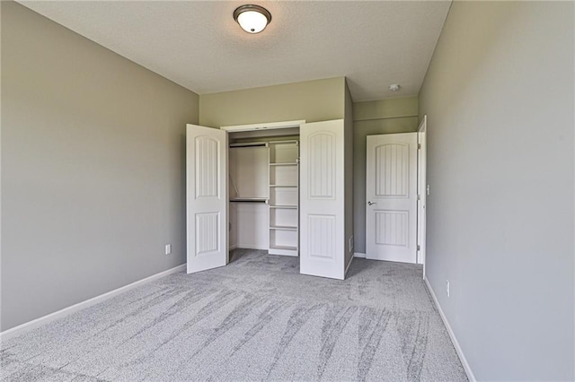 unfurnished bedroom with carpet floors, a textured ceiling, baseboards, and a closet