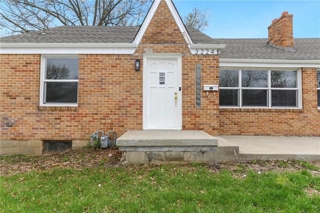 3224 E Barker Cir, Kansas City, KS 66104 - property entrance featuring a chimney, brick siding, and a shingled roof