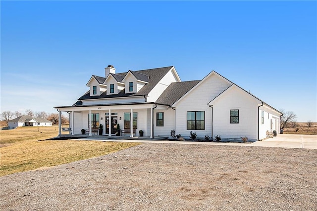 modern farmhouse featuring covered porch and a front yard