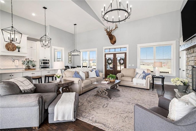 living area with dark wood finished floors, a fireplace, an inviting chandelier, and a towering ceiling