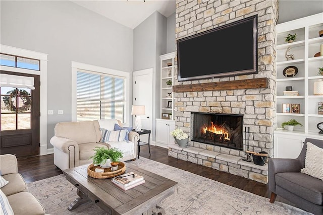 living room with built in shelves, baseboards, a fireplace, wood finished floors, and high vaulted ceiling