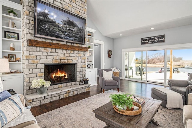 living room with built in features, high vaulted ceiling, a stone fireplace, and wood finished floors