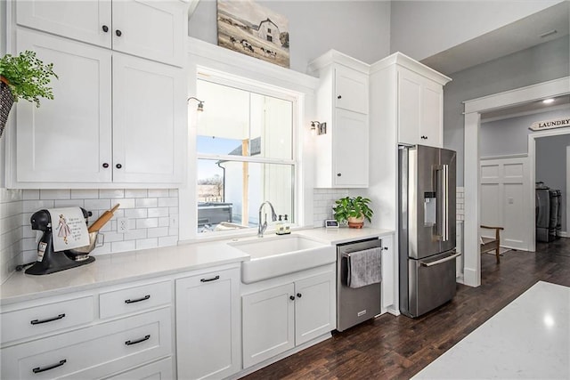 kitchen featuring dark wood finished floors, decorative backsplash, appliances with stainless steel finishes, white cabinets, and a sink