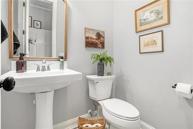 half bathroom featuring a sink, baseboards, and toilet