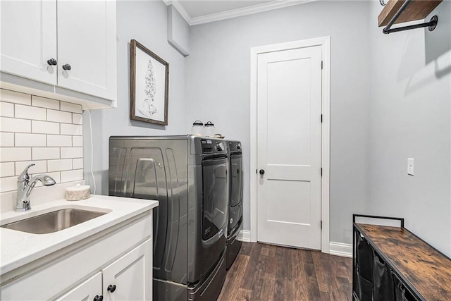 washroom featuring cabinet space, a sink, dark wood-type flooring, crown molding, and washer and clothes dryer