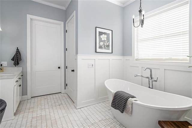 bathroom featuring a wainscoted wall, ornamental molding, a decorative wall, a soaking tub, and vanity