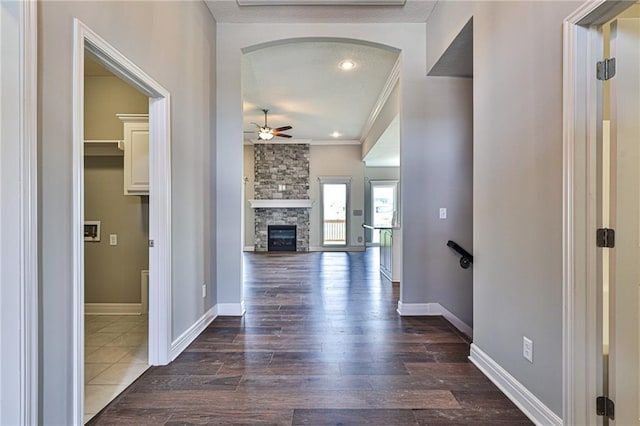 hallway with dark wood-style floors, arched walkways, crown molding, and baseboards