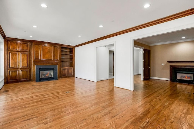 unfurnished living room with a glass covered fireplace, baseboards, and light wood-type flooring