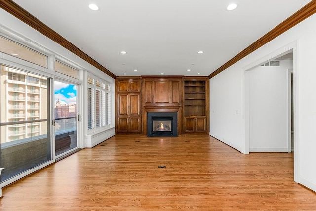 unfurnished living room with visible vents, a fireplace, light wood-type flooring, and ornamental molding