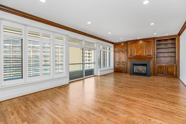 unfurnished living room with light wood finished floors, built in shelves, ornamental molding, recessed lighting, and a fireplace