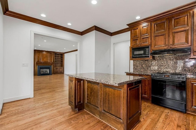 kitchen with under cabinet range hood, light wood-type flooring, decorative backsplash, a fireplace, and black appliances