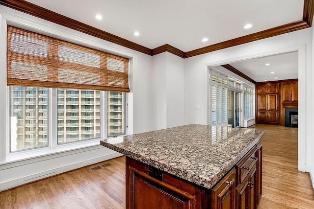 kitchen with visible vents, a fireplace, crown molding, and light wood-style floors