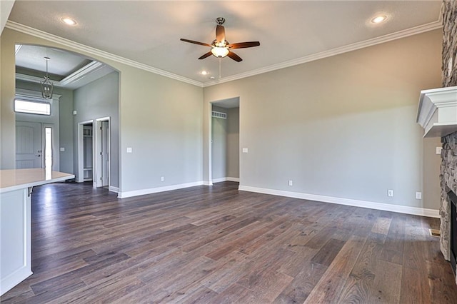 unfurnished living room with a fireplace, dark wood finished floors, a ceiling fan, and crown molding