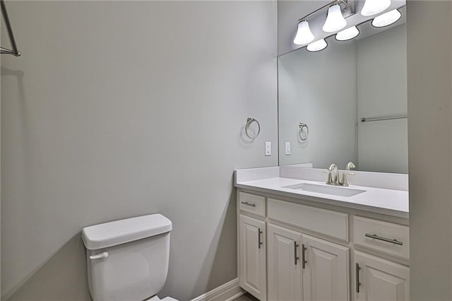 bathroom featuring baseboards, vanity, and toilet