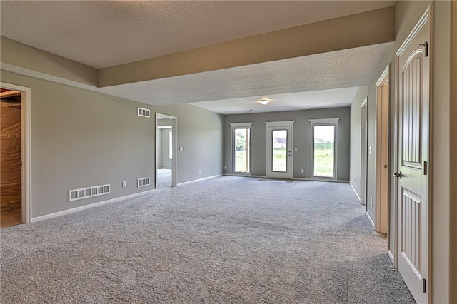 carpeted empty room featuring a textured ceiling, visible vents, and baseboards