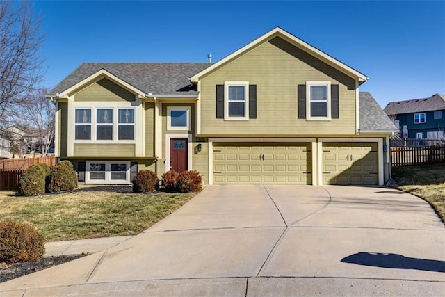 view of front facade with a garage, a shingled roof, concrete driveway, fence, and a front lawn