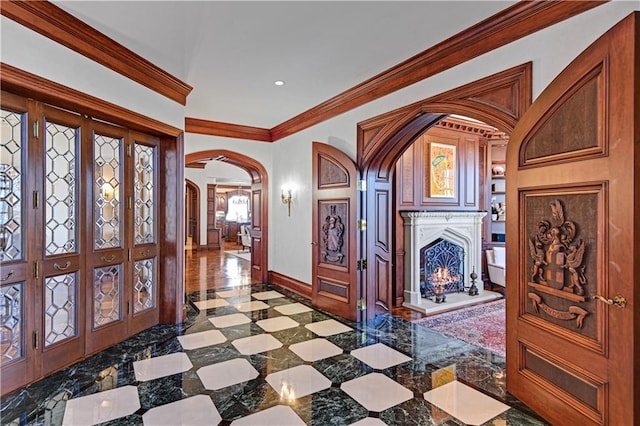 entrance foyer with arched walkways, recessed lighting, ornamental molding, a lit fireplace, and baseboards