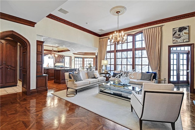 living area with a wealth of natural light, visible vents, a high ceiling, and an inviting chandelier