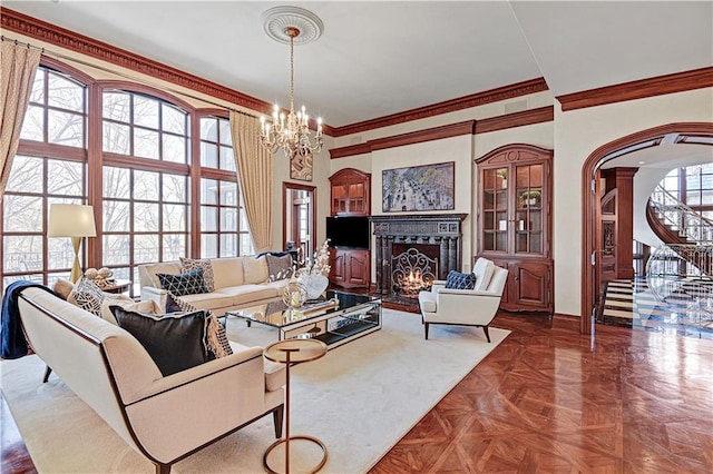 living room with arched walkways, a lit fireplace, stairway, and a wealth of natural light