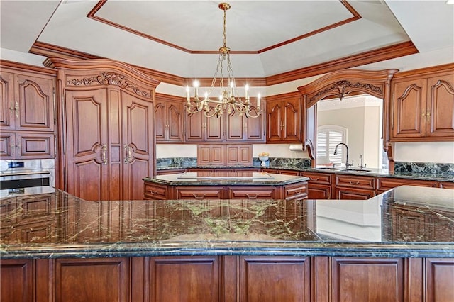 kitchen with a center island, a raised ceiling, stainless steel oven, and a sink