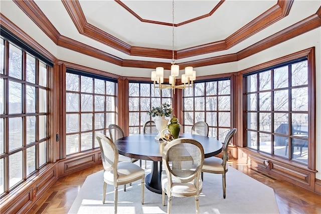 dining room with a chandelier, ornamental molding, and a raised ceiling