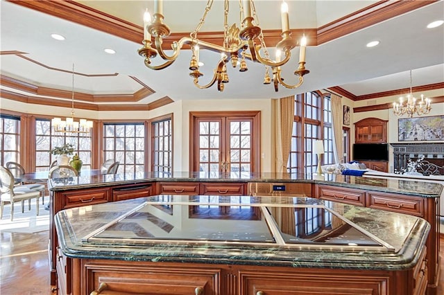 kitchen with a large island, brown cabinets, crown molding, french doors, and a notable chandelier