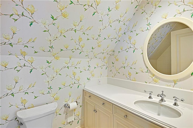 bathroom featuring toilet, wallpapered walls, and vanity