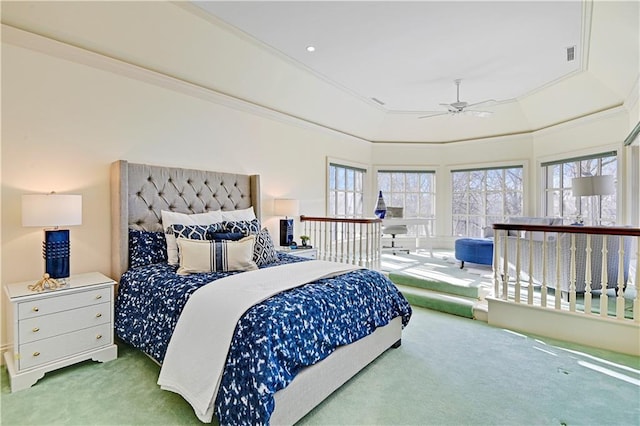 carpeted bedroom featuring a tray ceiling, multiple windows, a ceiling fan, and crown molding