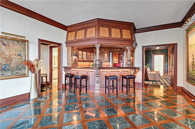 kitchen featuring ornamental molding, dark countertops, a kitchen breakfast bar, and baseboards