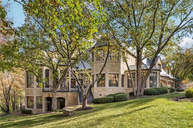 view of front of home with a standing seam roof, stone siding, metal roof, and a front yard