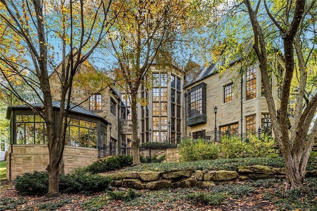 exterior space with stone siding, metal roof, a standing seam roof, and fence