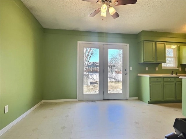 kitchen featuring green cabinets, light countertops, plenty of natural light, and baseboards