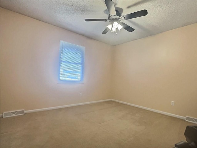 spare room featuring visible vents, light colored carpet, and a textured ceiling