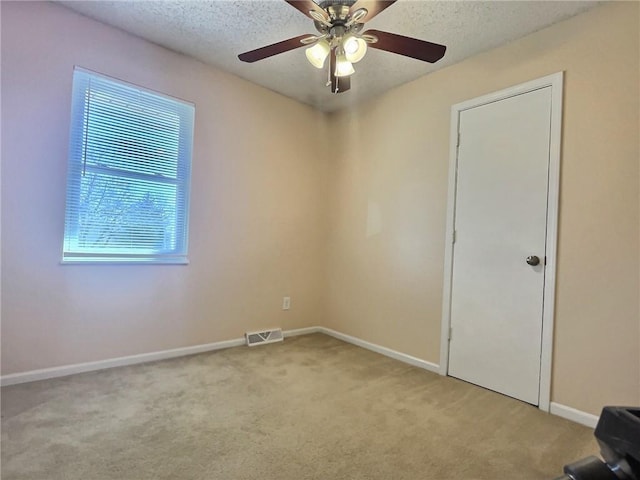 unfurnished room featuring visible vents, a ceiling fan, a textured ceiling, carpet, and baseboards