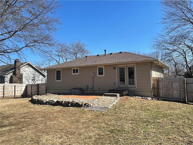 back of property featuring a yard, roof with shingles, french doors, and fence