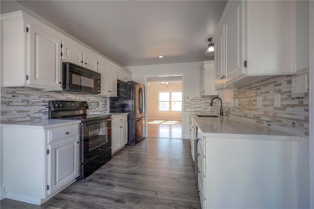 kitchen featuring wood finished floors, a sink, white cabinetry, light countertops, and black appliances