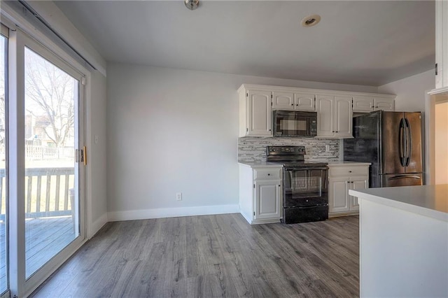 kitchen with light countertops, decorative backsplash, white cabinetry, wood finished floors, and black appliances