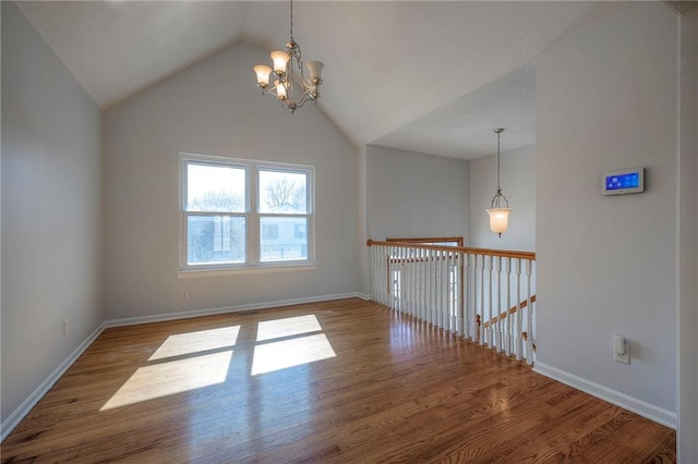 unfurnished room featuring vaulted ceiling, a notable chandelier, baseboards, and wood finished floors