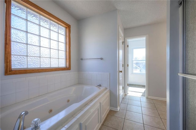 full bath with baseboards, a tub with jets, a textured ceiling, and tile patterned floors