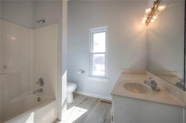 bathroom with visible vents, toilet, wood finished floors, vanity, and shower / washtub combination