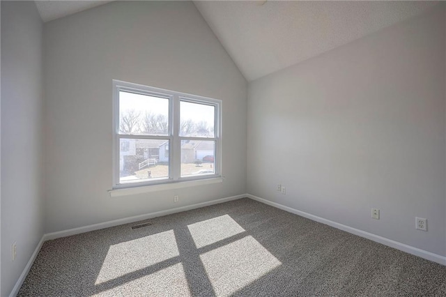 empty room with carpet flooring, vaulted ceiling, visible vents, and baseboards