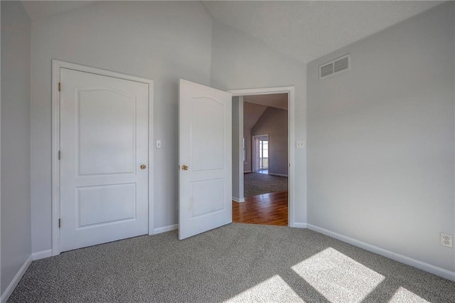 unfurnished bedroom with lofted ceiling, carpet, visible vents, and baseboards