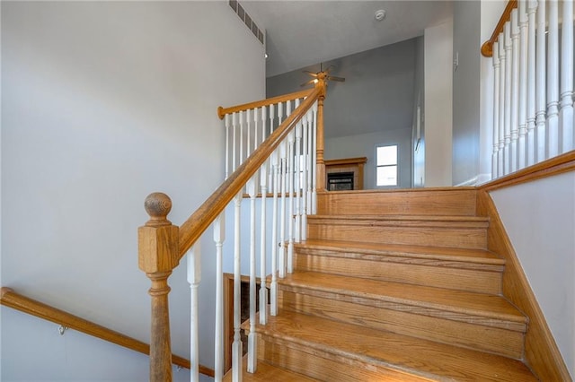 stairs with visible vents, ceiling fan, and a fireplace